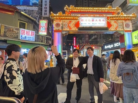 饒河街觀光夜市（台北）にて、成城大学の教員2名が学生に促されて記念撮影。学生たちと一緒に最後の夜を楽しみました。学生と教員の垣根が低いのも、社会イノベーション学部の特徴の一つです。